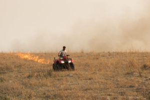 rancher using an ATV to start a burn