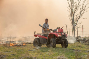 rancher using an ATV to start a burn