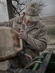 Rancher pouring mix of gasoline and kerosene in drip torch