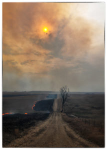 Smoke darkening sky above country road