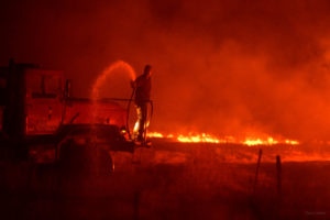 Rancher controlling burn using water spray from large truck