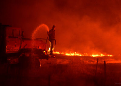 Rancher controlling burn using water spray from large truck