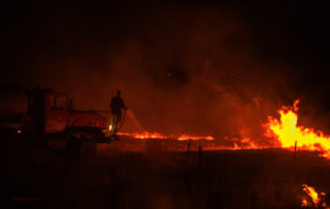 Rancher spraying water to control a burn