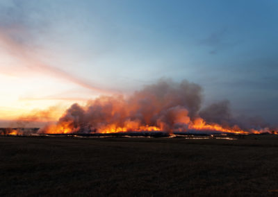Flames and smoke above charred section prairie
