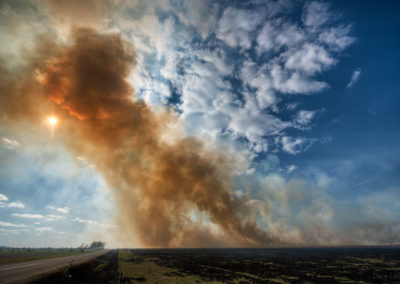 Smoke rising against the sun from controlled prairie burn